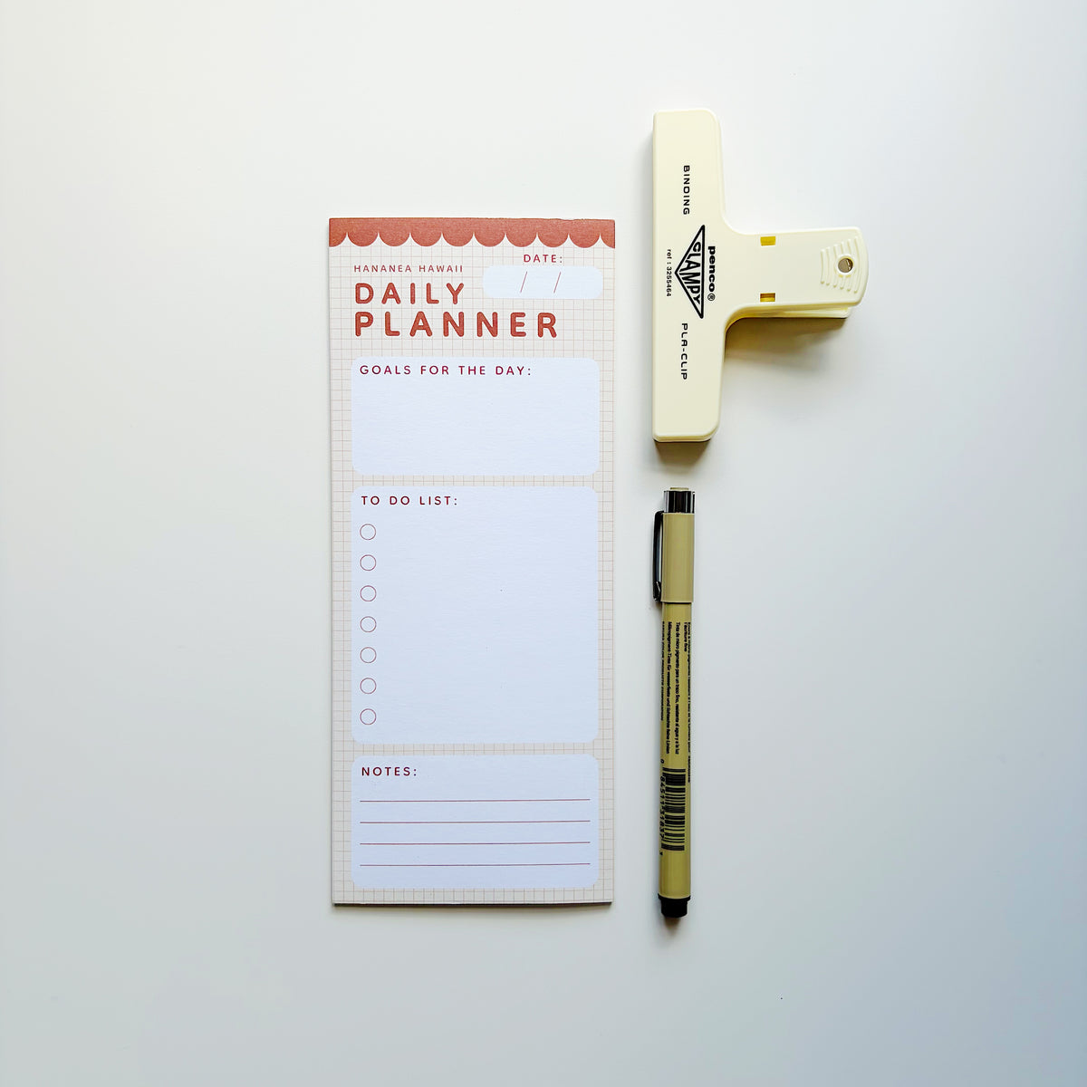 A daily planner notepad with a to-do list and notes section, styled in a flat lay with a beige highlighter and a black pen on a light gray background.