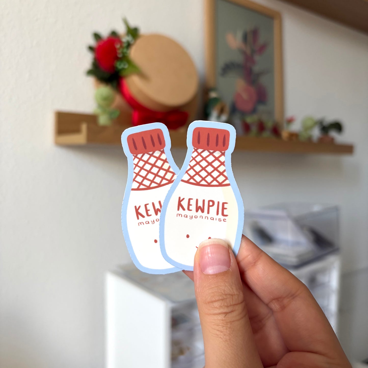 Hand holding a Kewpie mayonnaise sticker in a kitchen setting