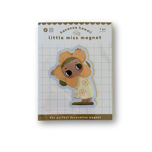 A packaged decorative magnet featuring a cute cartoon character in a yellow outfit on a white grid background.