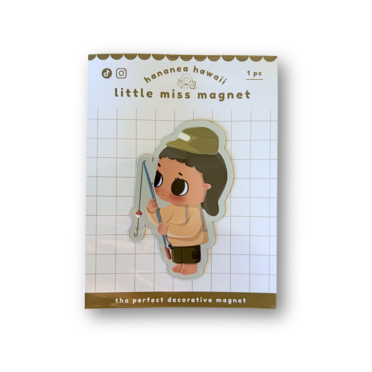 A packaged decorative magnet featuring a cute cartoon girl character holding a fishing rod, displayed on a white grid backing card with brown text and border details.