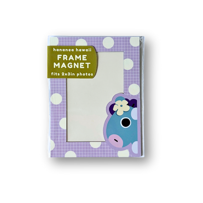 A frame magnet shown in its packaging against a white background. The magnet features a purple and white checkered pattern with white polka dots, a green label, and a blue cartoon character wearing a flower.