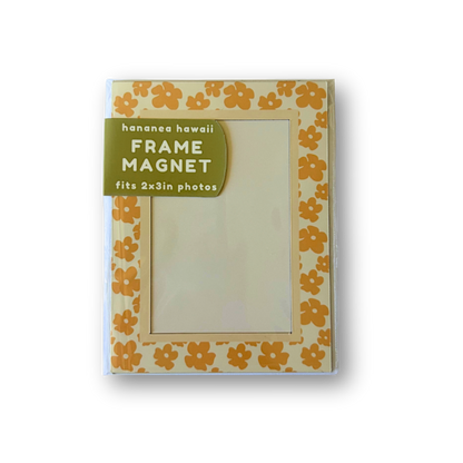 A packaged frame magnet, featuring a cream background with a yellow-orange puakenikeni border.