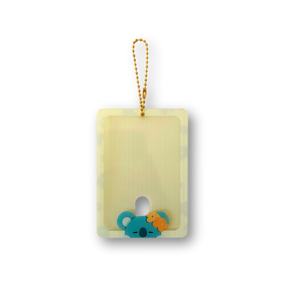 A rectangular translucent pale yellow acrylic card holder with a gold-tone hanging loop and a small koala-shaped ornament at the bottom, shown on a plain white background.