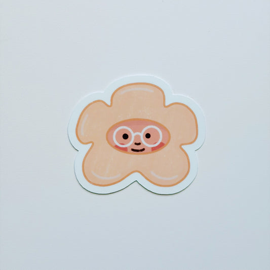 A cute, puakenikeni sticker featuring a smiling face with round glasses, set against a plain light gray background.