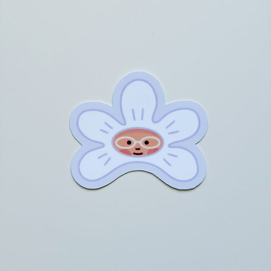 A die-cut sticker of a smiling cartoon flower with a face peeking out from the center, shown on a plain light gray background.