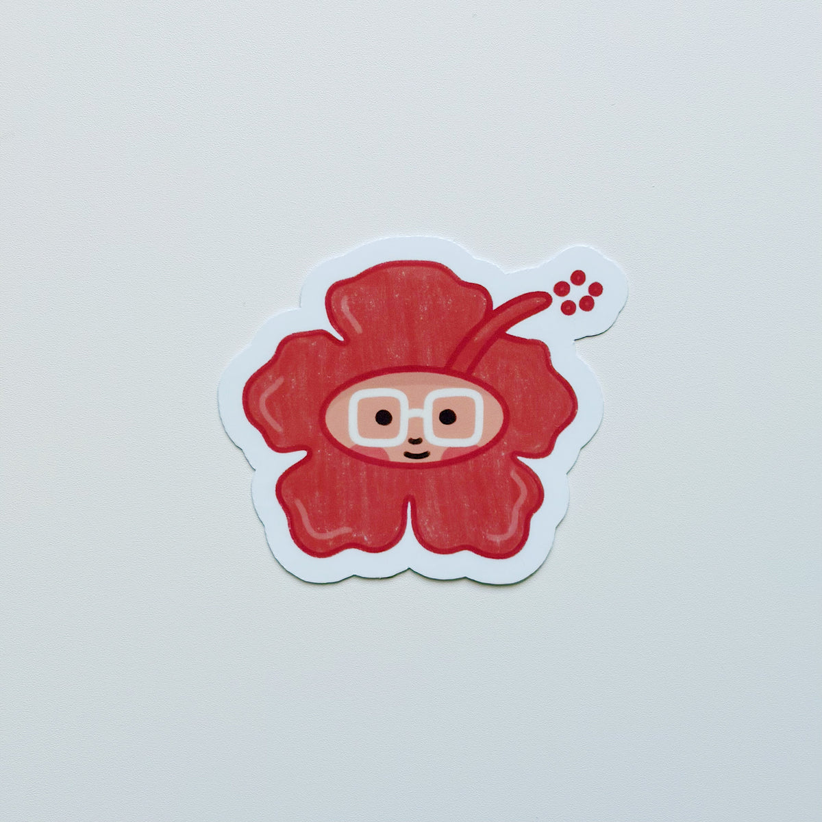 A die-cut sticker featuring a cute cartoon flower character with a face and glasses, set against a plain light gray background.