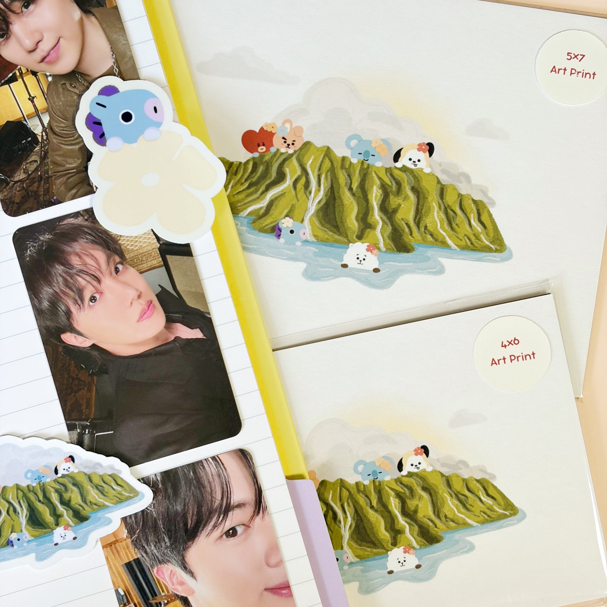 Art prints featuring cartoon animal illustrations on green hills, arranged on a beige background with some decorative paper and photo inserts.
