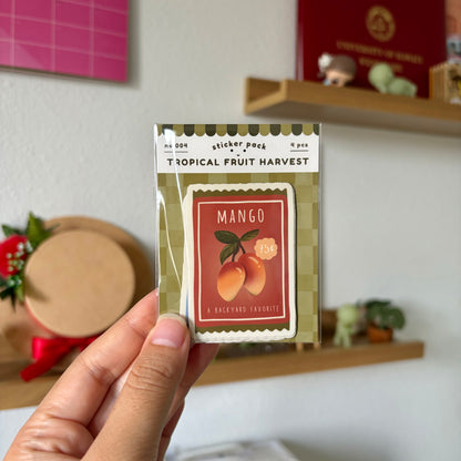 Tropical Fruit Harvest sticker pack held in front of a shelf with decorative items.