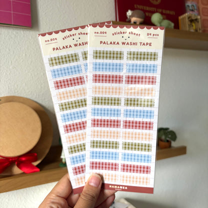 Two sticker sheets with palaka held by a hand against a blurred indoor background.