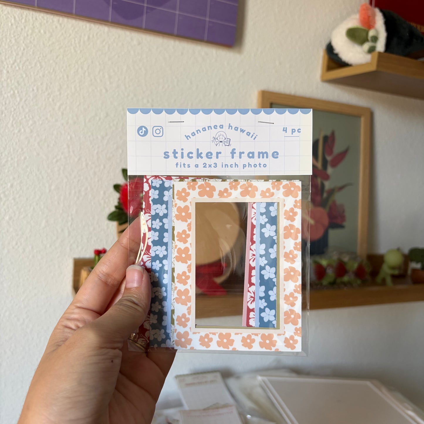 A hand holds a packaged set of four sticker frames.