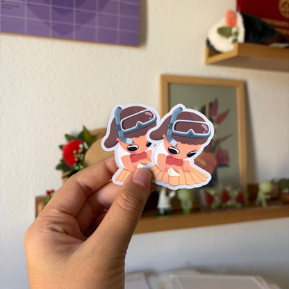 A hand holds two small die-cut stickers featuring cartoon characters.