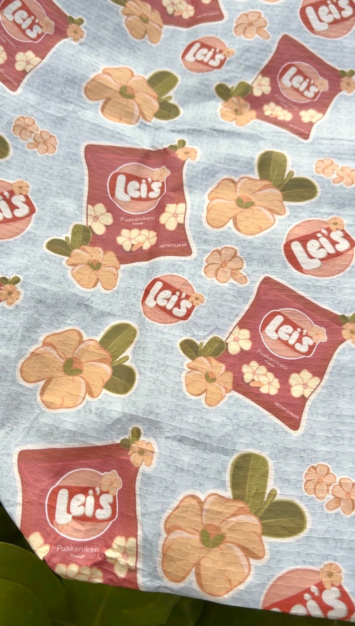 Patterned fabric with 'Lei's' packaging and floral designs on a blue background