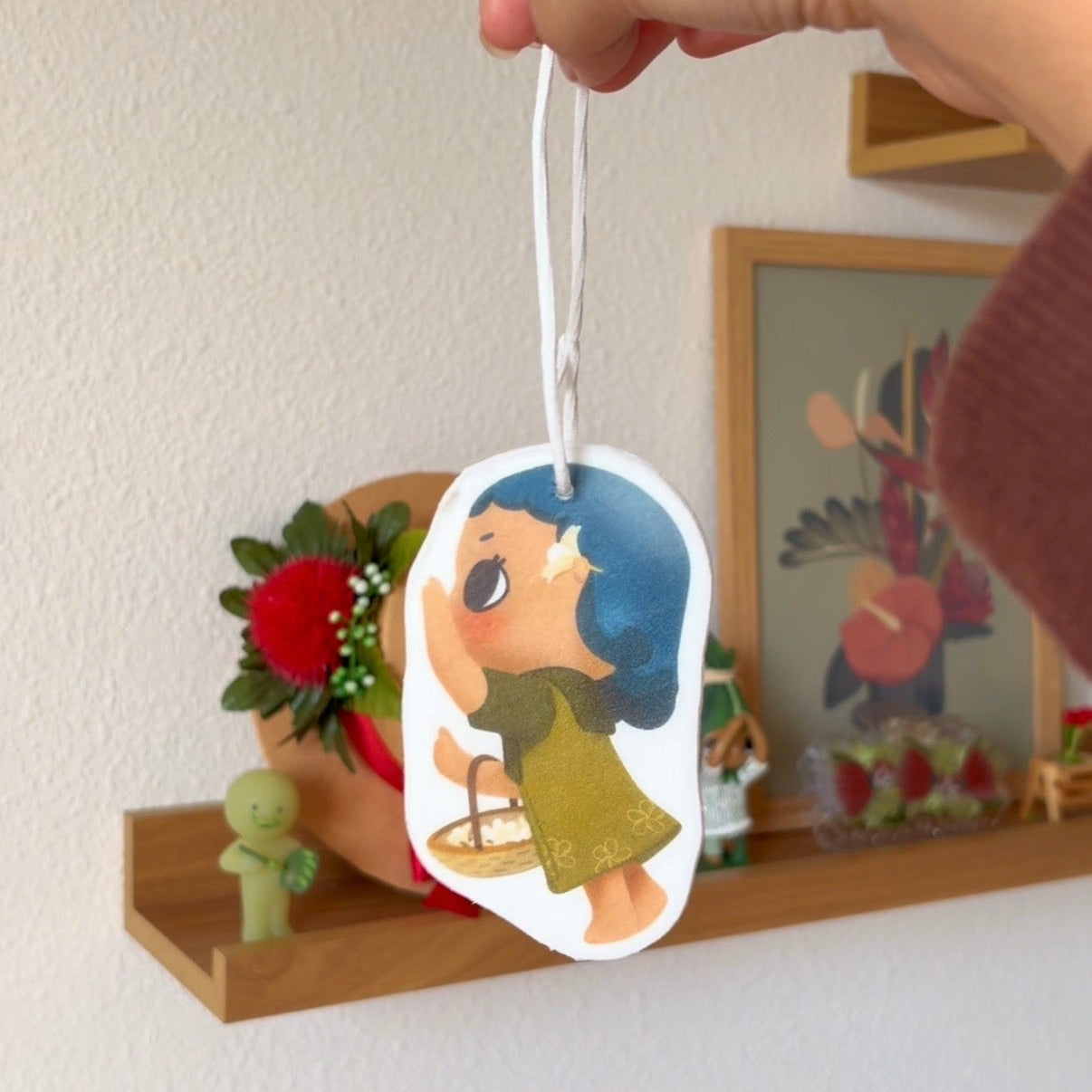 Hand holding a decorative freshener with an illustration of a character.