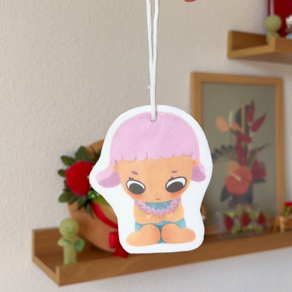 Cartoon character air freshener hanging by a hand with a decorative background