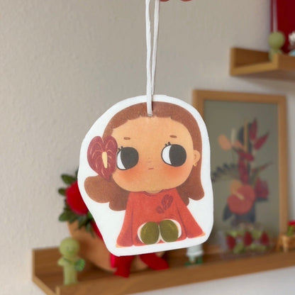 Cartoon character air freshener held by a hand with a decorative background
