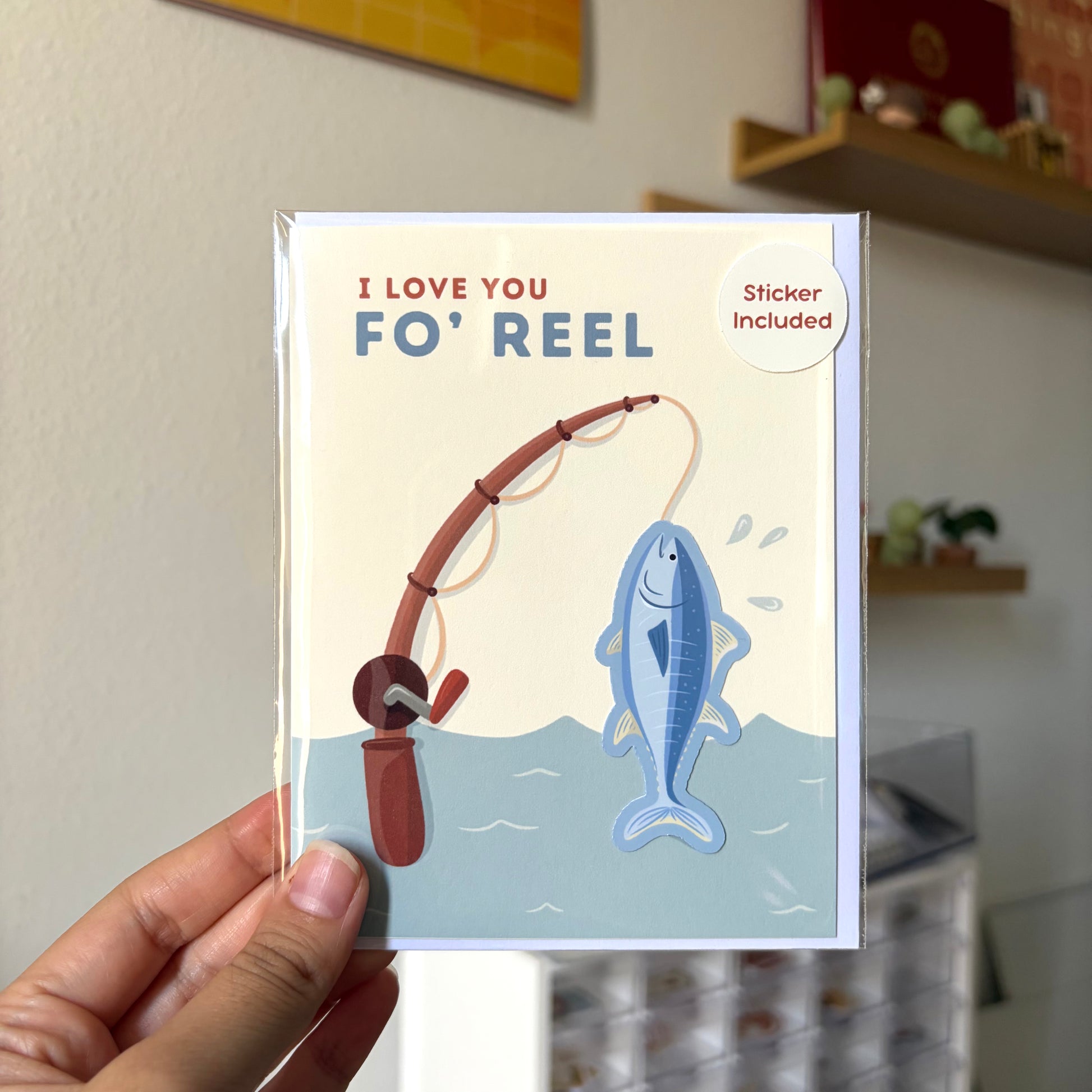 Card with fishing illustration and text 'I Love You Fo' Reel' held by a hand.