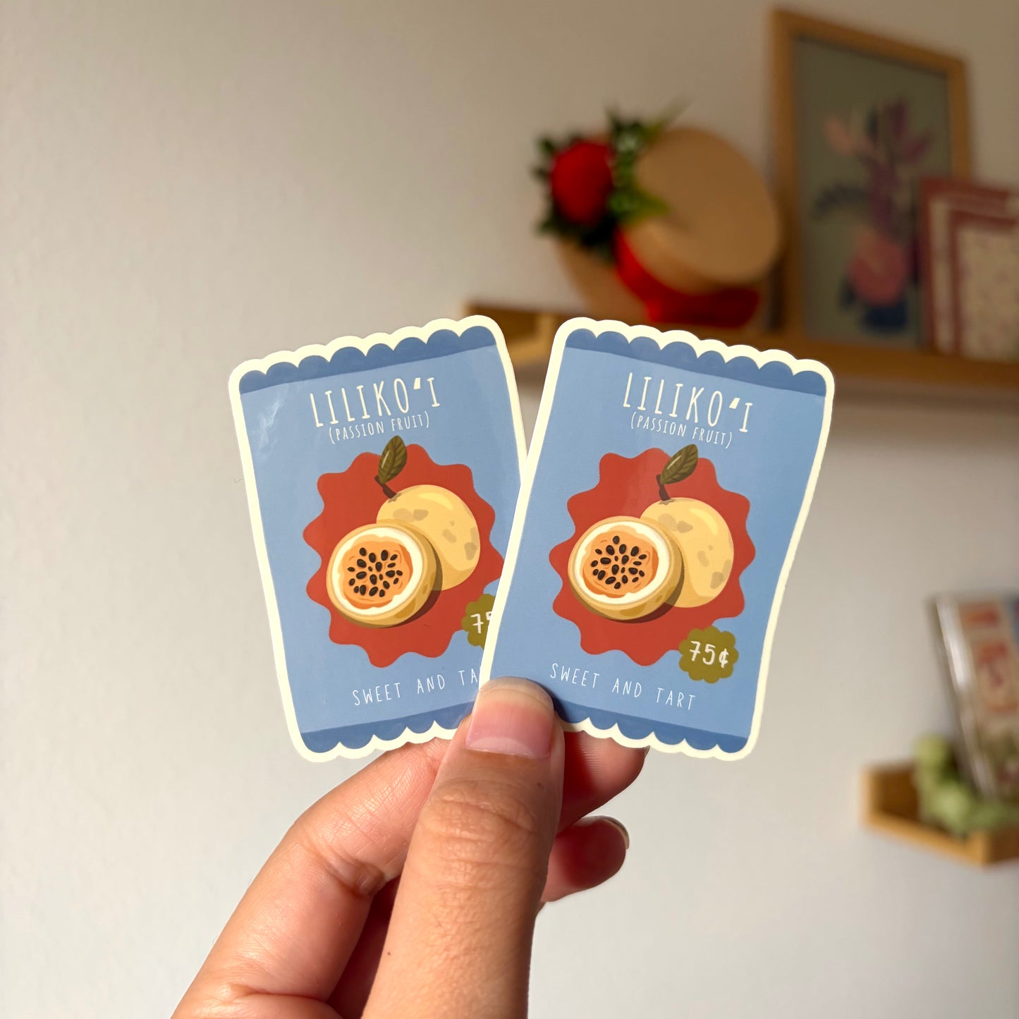 Two small cards with fruit illustrations held by a hand against a neutral background.